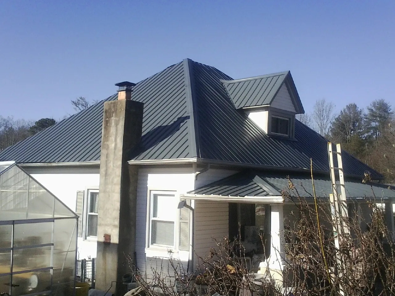 Dark blue standing seam metal roof on a white farmhouse with dormer — Slate & Tile Roof Repair by Roofing Brothers in Rushville