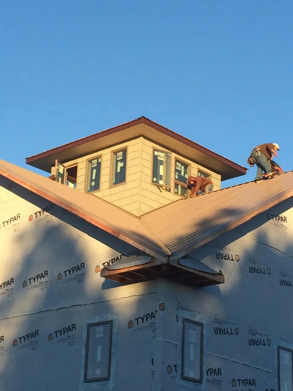 Roofers working around a rooftop cupola on a new metal roof at sunset — Roof Waterproofing in Rushville by Roofing Brothers